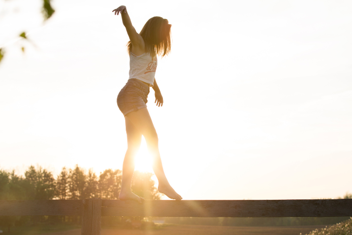 Ragazza che cammina in equilibrio su una trave, simbolo di concentrazione e controllo.