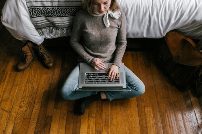 Ragazza seduta a terra con un computer sulle gambe, simbolo di accessibilità digitale e contenuti fruibili ovunque.